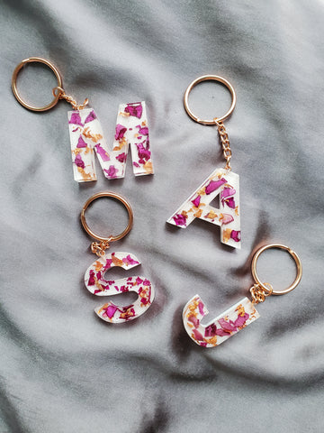 custom letter keychain made of resin, real pink rose petals and rose gold flakes with a white base